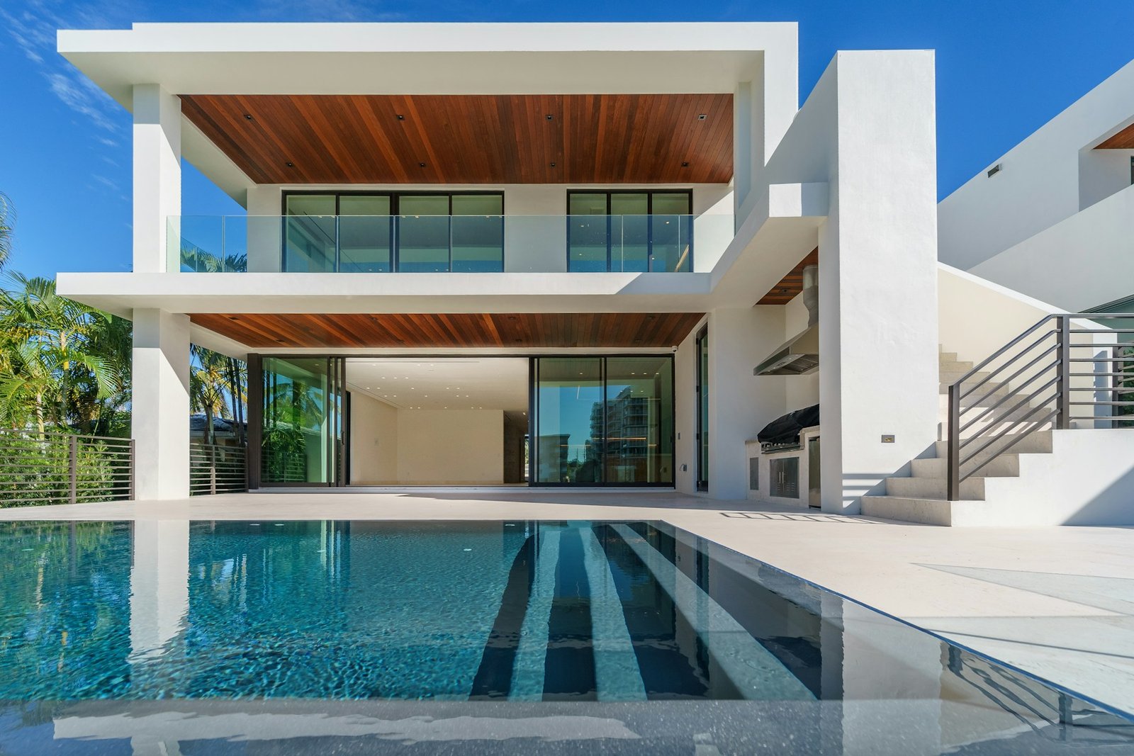 A modern white home with timber details and a swimming pool.